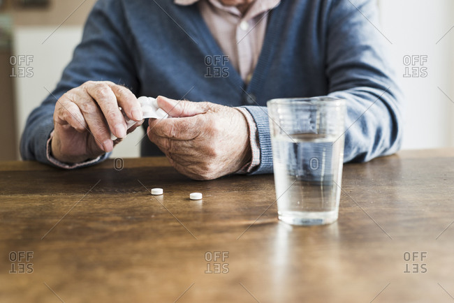 Hands of senior man taking tablets out of blister pack, close-up