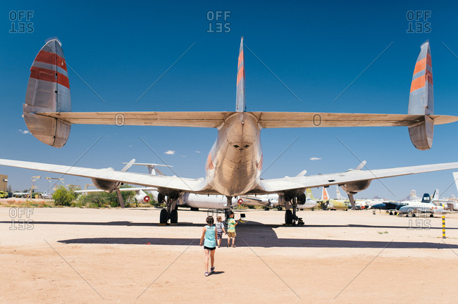 Back view of three children exploring a plane at air show