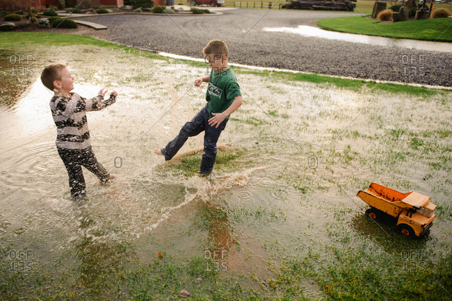 Two young boys play in puddle in flooded front yard