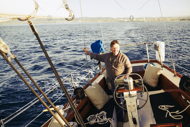 Man standing at the captain\'s wheel on a sailboat