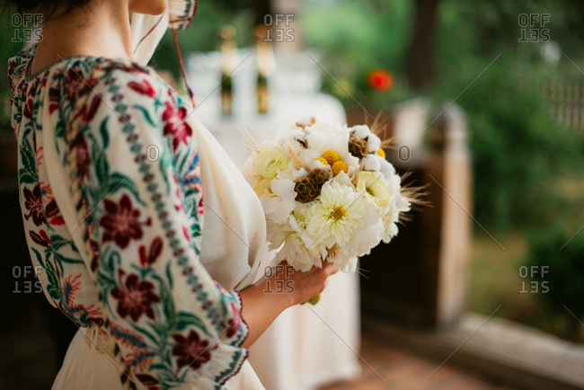 Close-up of bride in Romanian embroidered blouse holding her wedding bouquet