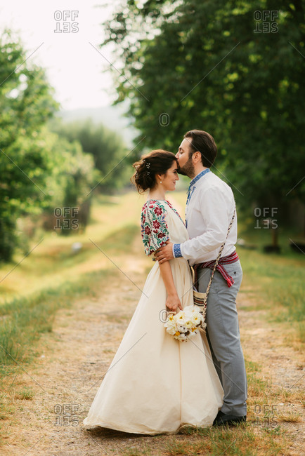Portrait of bride and groom kissing at traditional folk wedding on Romanian farm
