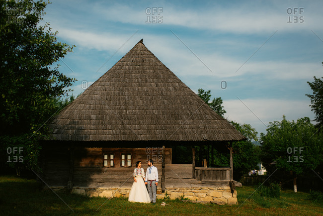 Portrait of a Romanian bride and groom standing at a farm cottage