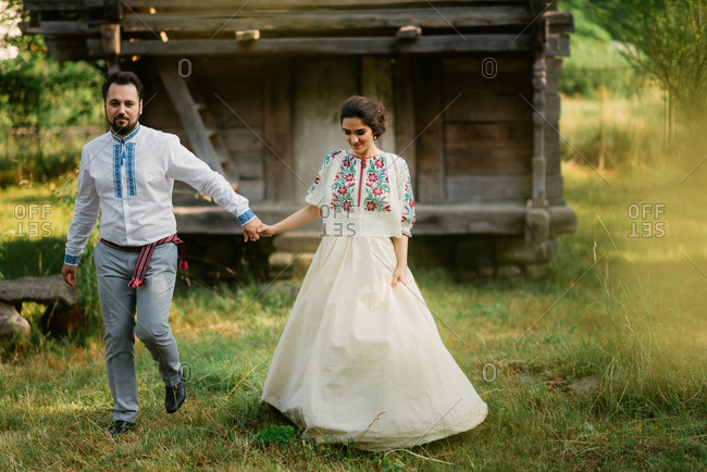 Romanian bride and groom walk hand-in-hand at country wedding