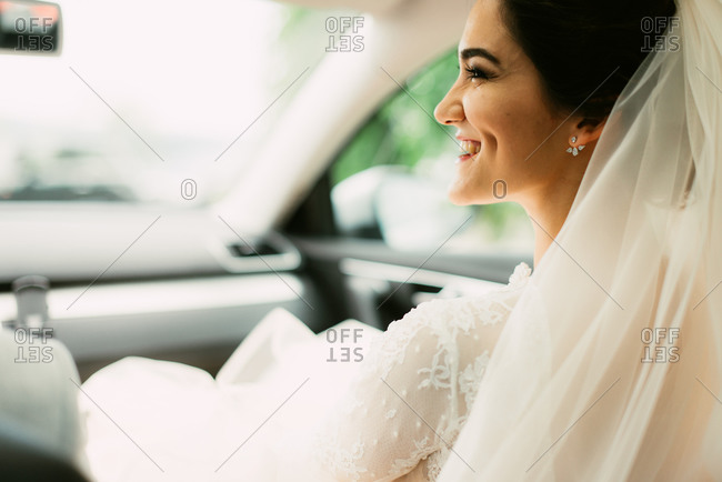 Smiling bride sitting in front seat of car