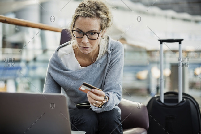 Businesswoman using credit card and laptop at airport lobby
