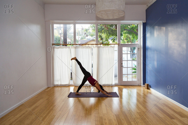Woman in a yoga studio in a one legged downward-facing dog pose