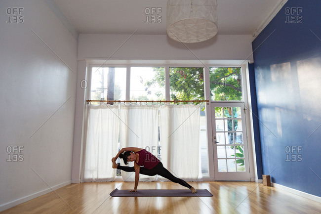 Woman in a yoga studio in a monkey side plank pose