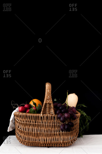 Side view of a basket filled with fruits and vegetables on a table