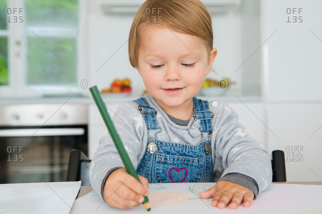 Female toddler drawing at kitchen table