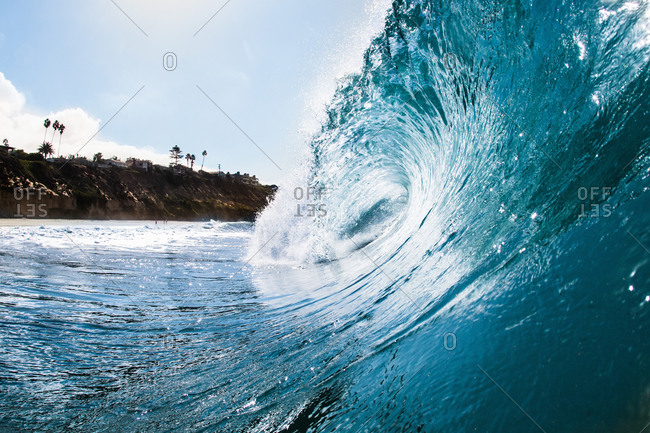 Surface level view of rolling ocean wave and coastline. Encinitas, California, USA