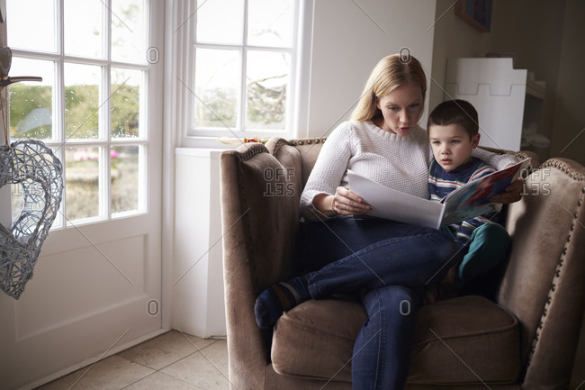 Mom sitting in chair at home reading story to her son