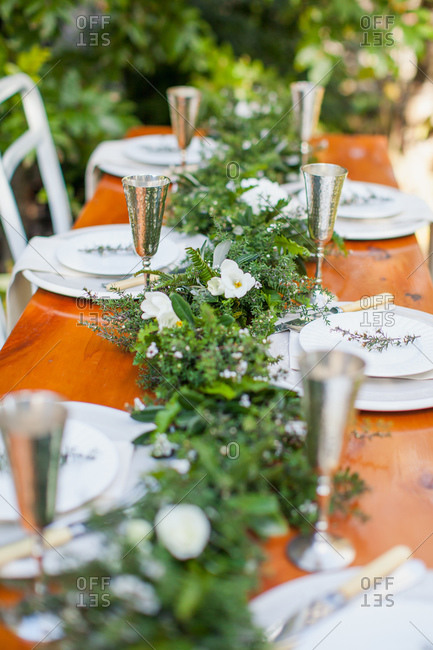 Dining table set with garland of greenery for outdoor wedding reception