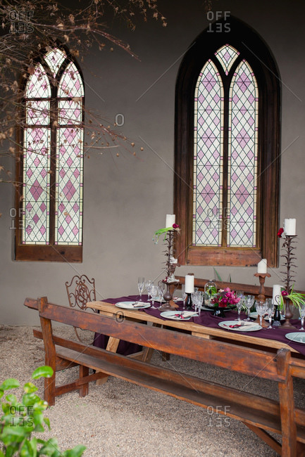 Rustic wooden dining table set next to gothic stained glass windows