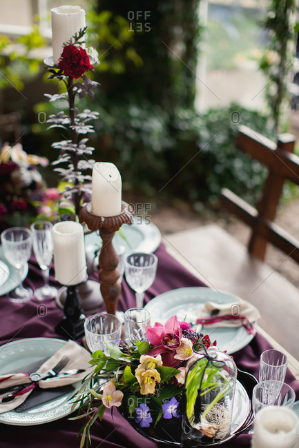 Table set with pillar candles and flower arrangements on burgundy cloth
