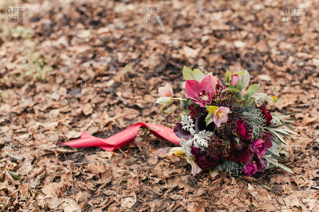 Burgundy floral bouquet resting on brown fallen leaves