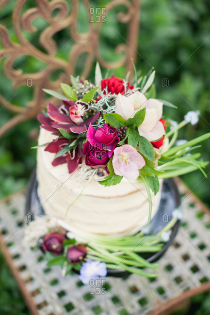 Close-up of cake topped with burgundy flowers on chair