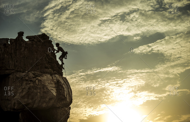 Rock climber silhouetted on cliff