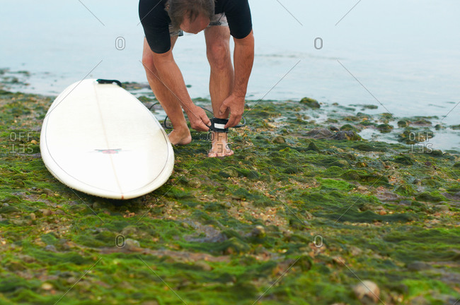 Surfer attaching surfboard leash to ankle