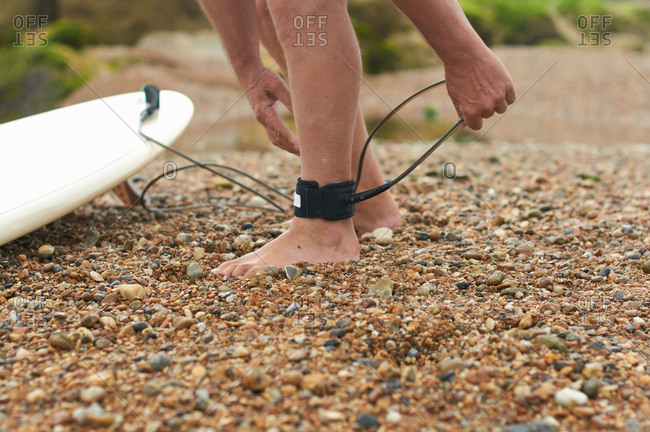 Surfer tying surfboard leash to ankle