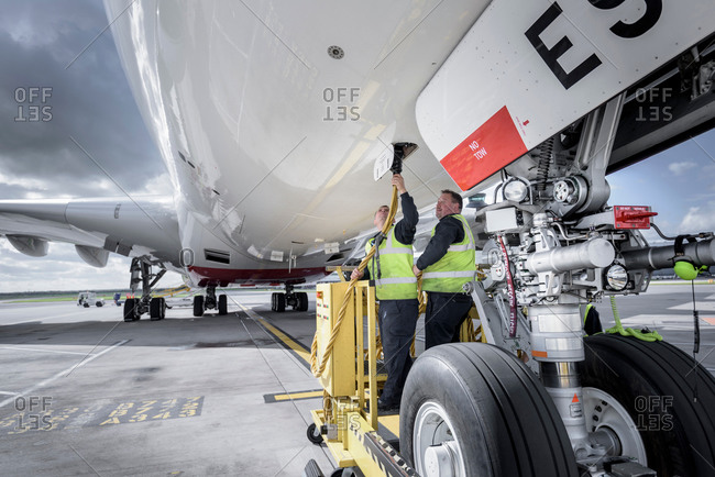 Ground crew affixing loading equipment on an aircraft