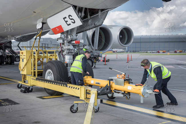 Ground crew fixing tow bar onto an aircraft at an airport