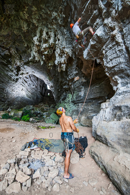 Male climbers climbing treasure cave in Yangshuo, Guangxi Zhuang, China