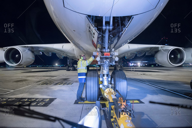 Chief engineer inspecting an aircraft on runway at an airport at night