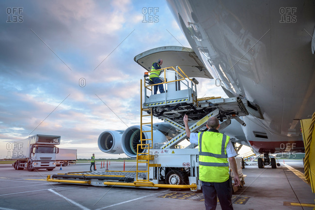 Ground crew attending to an aircraft with freight loader at an airport
