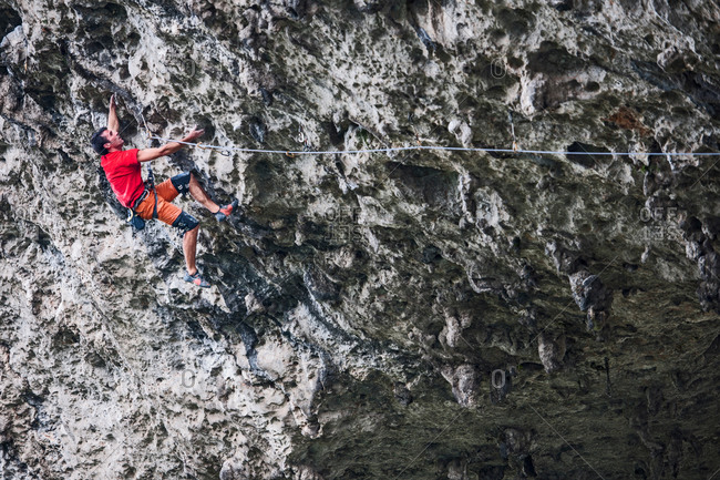 Male climber climbing the route Lunatic on Moon Hill in Yangshuo, Guangxi Zhuang, China