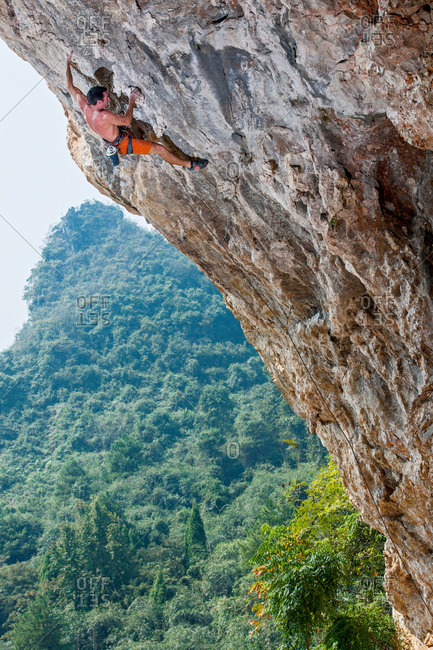 Male climber climbing overhang at Odin's Den next to Moon Hill in Yangshuo, Guangxi Zhuang, China