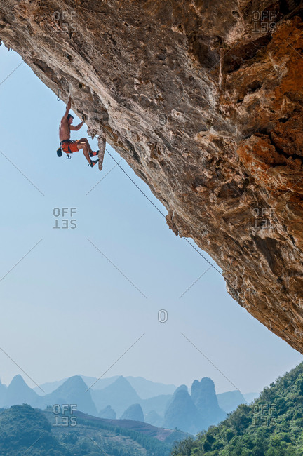 Male climber climbing at Odin\'s Den next to Moon Hill in Yangshuo, Guangxi Zhuang, China