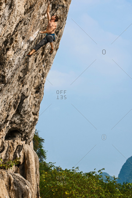 Low angle view of male climber climbing at white Mountain - a limestone cliff in Yangshuo, Guangxi Zhuang, China