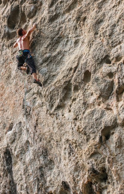 Male climber climbing at white Mountain - a limestone cliff in Yangshuo, Guangxi Zhuang, China
