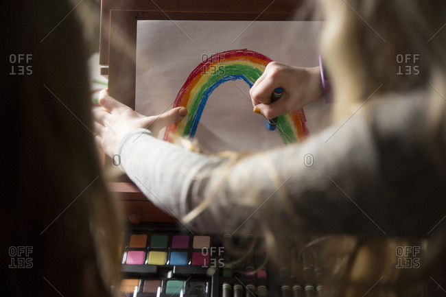 Girl using pastels to draw a rainbow
