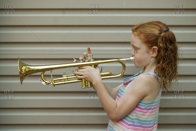 Red-haired young girl practicing trumpet