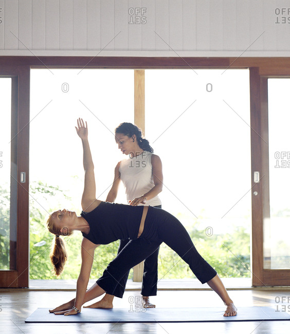 Yoga instructor helping a student with triangle pose during a yoga class