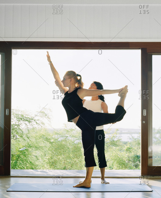 Yoga instructor helping a student with a pose during a yoga class