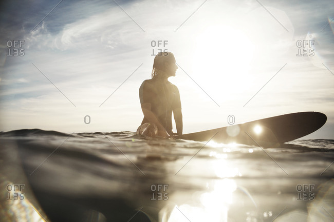 Woman sitting on her surfboard waiting for a wave