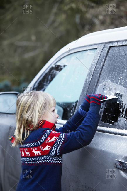Girl scraping ice from car window