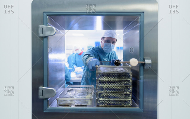 Worker putting surgical instruments into air lock in clean room of surgical instruments factory