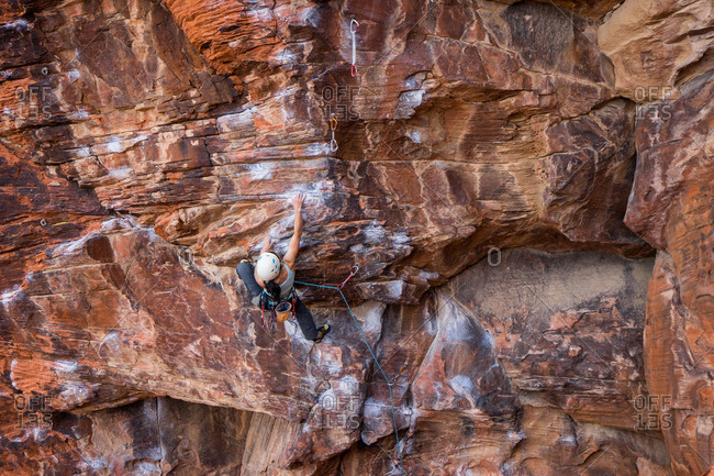 Climber scaling a sandstone rock face at Red Rock Canyon, Nevada