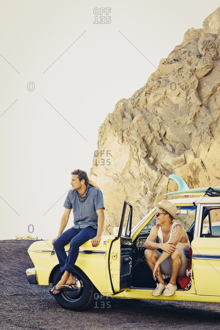 Two men in vintage car parked on beach