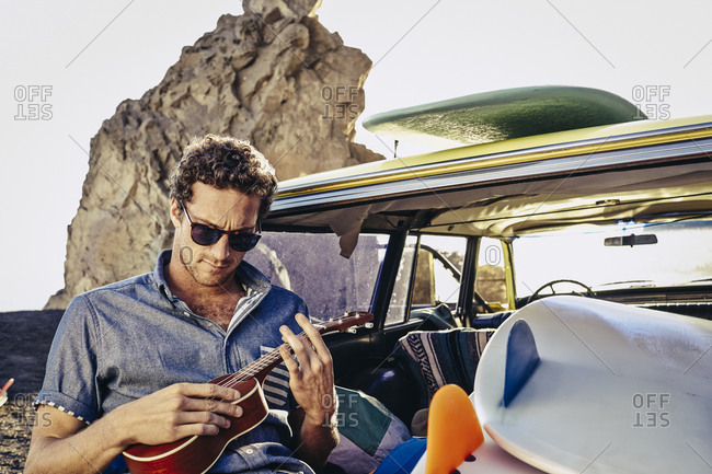 Man plays ukulele in back of vintage surf wagon