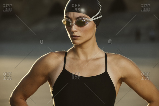 Competitive swimmer standing in golden light on beach