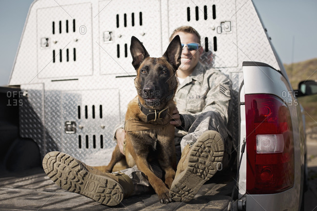 Air Force Staff Sergeant with his trained dog in the bed of a truck