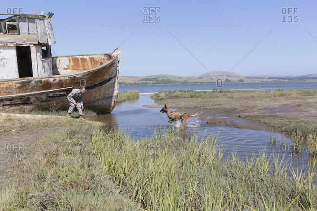 Soldier working with his Military Service Dog near old boat