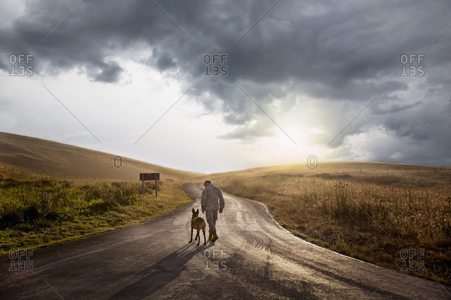Soldier and his service dog walking down road at end of day