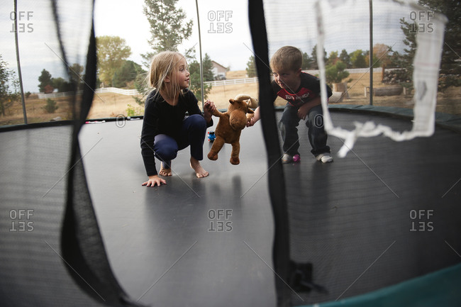 Children playing with a stuffed moose on a trampoline