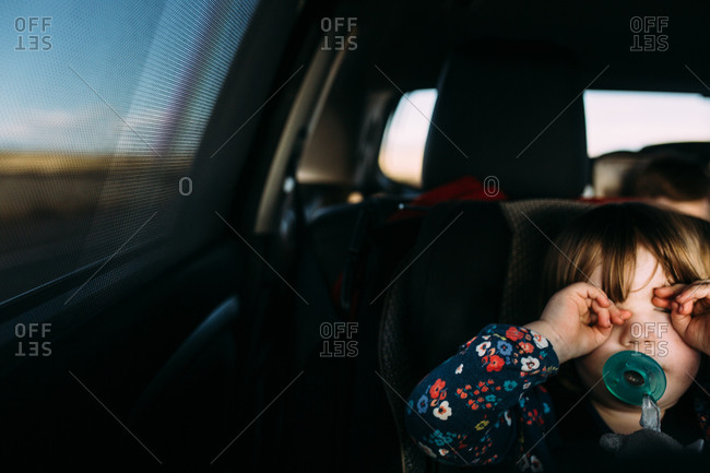 Girl rubbing eyes in car